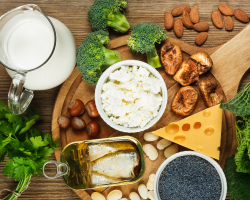 A spread of cheese, nuts, broccoli and other foods, with a pitcher of milk nearby.